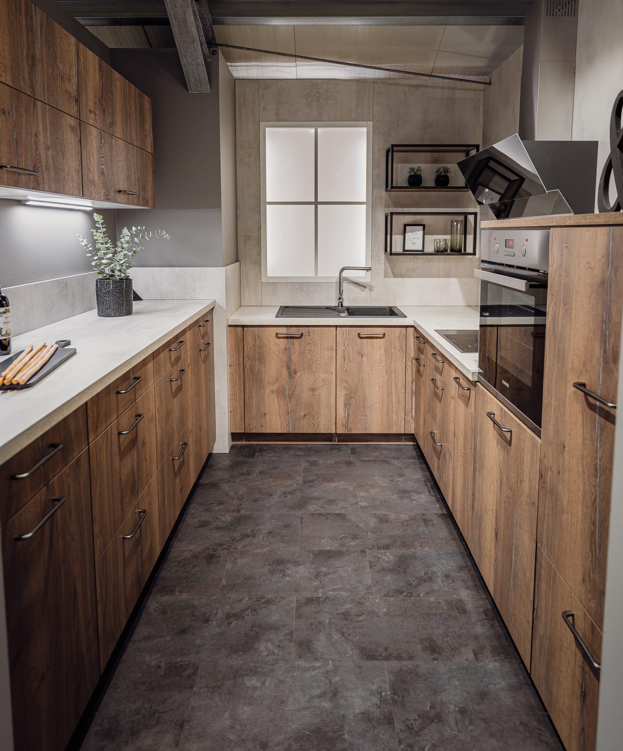 Das Bild zeigt eine Küche in U-Form mit Holzfronten und einer hellen Arbeitsplatte.